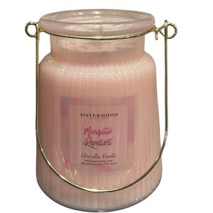 May include: A pink citronella candle in a glass jar with a gold-colored metal handle. The candle has a label that reads "Mosquito Repellant" and "Citronella Candle". The candle is hand-poured in TX and weighs 10.04 oz.