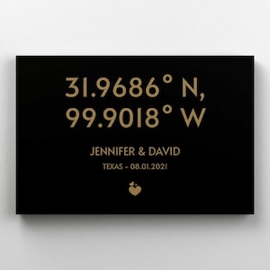 May include: Black canvas print with gold text. The text reads "31.9686° N, 99.9018° W, Jennifer & David, Texas - 08.01.2021". There is a small gold heart symbol at the bottom.