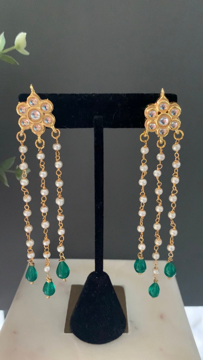 May include: Gold earrings with a floral design and white pearl and green gemstone accents.