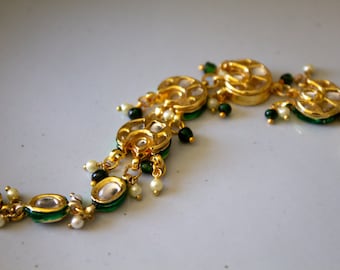 May include: A gold and green necklace with round, bejeweled pendants. The necklace features a repeating pattern of gold circles with clear stones and green accents.