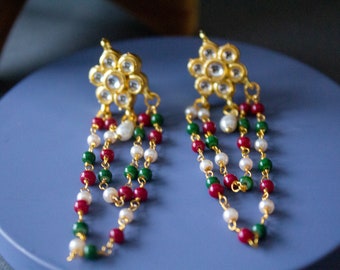 May include: A pair of gold earrings with a floral design and dangling chains of green, red, and white beads.