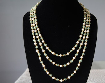 May include: A multi-strand necklace with alternating white and light green beads. The necklace is made of gold-toned metal.