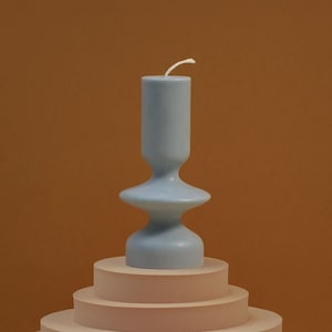 light blue vintage vase shaped candle on caramel brown background