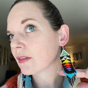 May include: A pair of long, colorful beaded earrings with a geometric pattern. The earrings are black, white, green, blue, yellow, orange, and red.