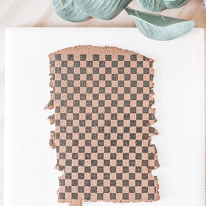 May include: A brown and black checkered patterned sheet of play dough on a white surface.