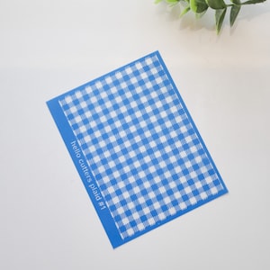 May include: A blue and white gingham patterned stencil with the text "hello cutters plaid #1" printed on the bottom left corner.