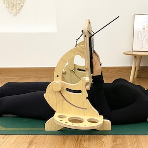 Può includere: Un supporto per laptop in legno con altezza e angolazione regolabili, progettato per l'uso sdraiati. Il supporto ha un porta bicchiere integrato e un porta telefono. Il supporto è realizzato in legno naturale e ha una finitura marrone chiaro.