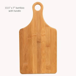 Op de afbeelding: Een 13,5 x 7 inch bamboe snijplank met een handvat. De plank is gemaakt van natuurlijk bamboe en heeft een lichtbruine kleur.
