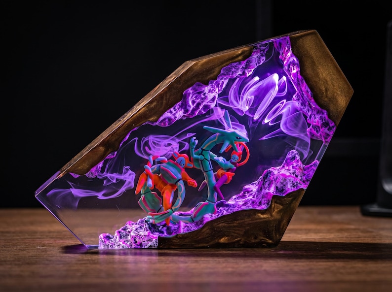 May include: A decorative resin and wood display piece featuring a translucent purple interior with swirling smoke-like patterns. Inside the clear resin, two small, detailed green and orange serpentine figures are positioned among textured purple rock formations.