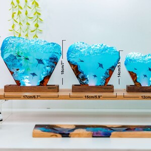 May include: Three resin lamps with a blue and white ocean scene and stingrays. The lamps are on a wooden base and are lit from the bottom. The lamps are 7.8 inches, 7 inches, and 5.5 inches tall.