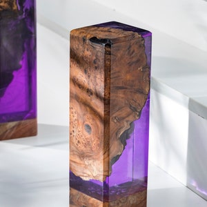 May include: A pair of rectangular wooden lamps with a striking design. The lamps feature a combination of natural wood grain and translucent purple resin. The wood has a rich, warm brown color, while the resin glows with a vibrant purple hue.