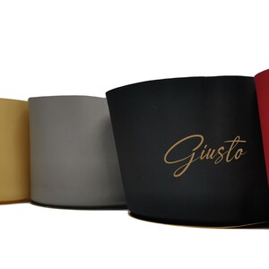 May include: A set of five cylindrical containers in navy, beige, gray, black, and red, each 4.75 inches tall. The black container features the word Giusto in gold script. Each container has a flat base and a smooth, solid-colored exterior finish.