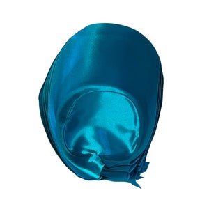 Peut inclure: Un n&oelig;ud en satin bleu sarcelle, pli&eacute; et nou&eacute; en forme arrondie.