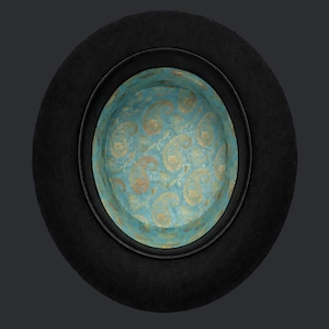 May include: A black top hat with a teal and gold paisley patterned interior. The hat has a black leather band around the brim. The hat is viewed from above.