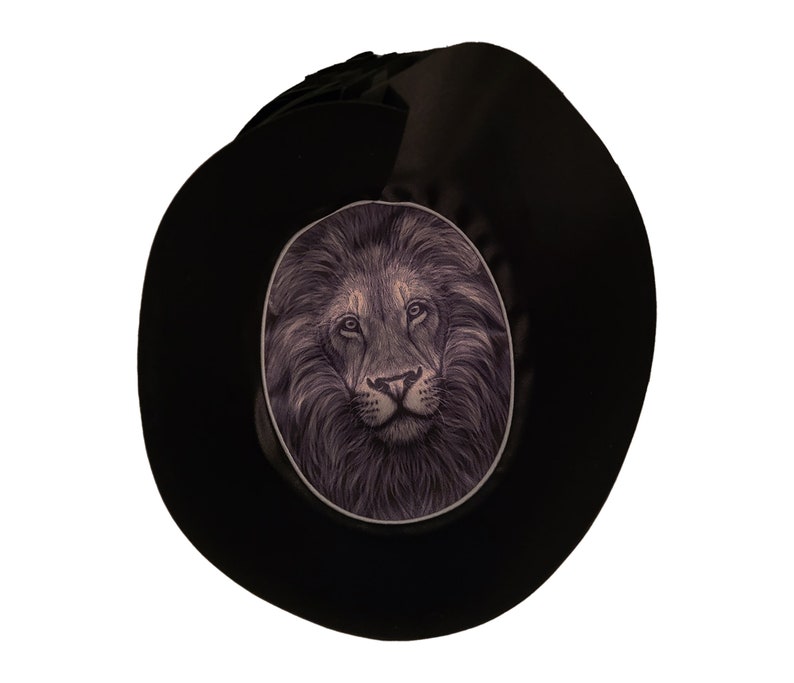 May include: A black fedora hat with a lion's face illustration on the front.