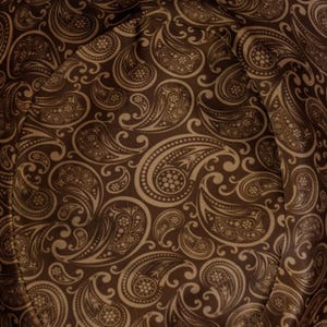 May include: Close-up of a brown fabric with a paisley pattern. The fabric has a soft, textured feel and is perfect for crafting projects.