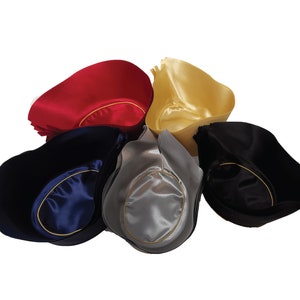 May include: A collection of five satin tricorn hats arranged in a circular pattern. The hats are available in red, gold, navy blue, silver, and black. Each hat features a smooth, shiny finish and a contrasting gold-colored trim along the inner brim.