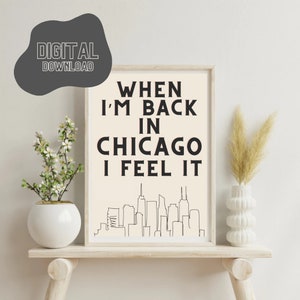 May include: A framed print with a white background and black text that reads "When I'm Back in Chicago I Feel It". The text is in a bold, sans-serif font. Below the text is a line drawing of the Chicago skyline.