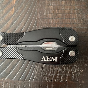 May include: Black multi-tool with a silver blade and the initials "AEM" engraved on the handle.