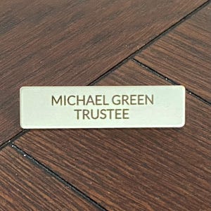 May include: A white rectangular name tag with the text "MICHAEL GREEN TRUSTEE" in gold lettering.