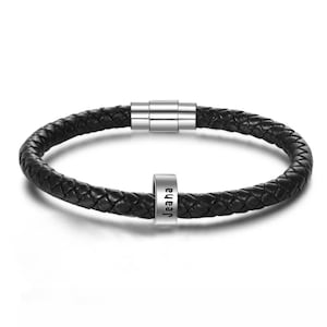 May include: Black leather bracelet with a silver magnetic clasp and a silver bead with the name "Jeaha" engraved on it.