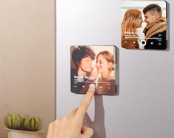 Könnte beinhalten: Zwei quadratische Magnete mit Fotos von Paaren, die wie Musikplayer-Oberflächen aussehen. Ein Magnet hat einen Finger, der eine Taste drückt. Der Text "Because You Live" ist sichtbar. Die Magnete befinden sich an einem silbernen Kühlschrank.
