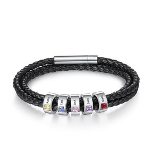 May include: Black leather bracelet with silver beads, each bead has a name engraved on it and a small gemstone. The names are Aalto, Tate, Jack, Sally, and Macy. The gemstones are yellow, blue, pink, purple, and red.