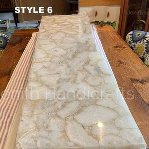 Puede incluir: Una losa de ágata blanca y beige con un acabado pulido. La losa es rectangular y tiene una superficie lisa y plana. La losa está sentada sobre una mesa de madera. El texto "STYLE 6" y "Jenith Handicrafts" es visible en la imagen.