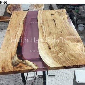 Op de afbeelding: Een houten tafelblad met een roze harsrivier die door het midden loopt. Het hout heeft een natuurlijke nerf en de hars is glad en glanzend. Het tafelblad is ongeveer 178 cm lang en 76 cm breed.