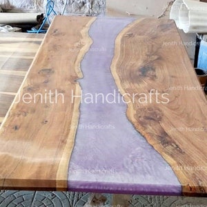 Op de afbeelding: Een houten tafelblad met een paarse harsrivier die door het midden loopt. Het hout is lichtbruin van kleur en de hars is lichtpaars van kleur. Het tafelblad is gemaakt door Jenith Handicrafts.