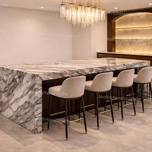 May include: A contemporary kitchen island featuring a marble worktop and a dark wood base. Five beige upholstered bar stools with black legs are positioned along the island. A chandelier hangs above.