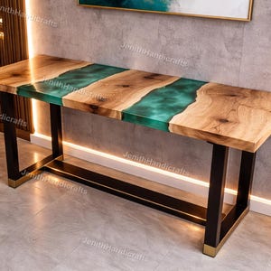 May include: A rectangular wooden console table with a teal epoxy resin center. The table has a natural wood grain finish on the sides and a black metal frame with gold accents on the legs. The table is a modern design.