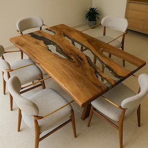 May include: A rectangular wooden dining table with a live edge design and a clear resin inlay. The table is surrounded by six light gray upholstered chairs with wooden legs and gold-colored arm supports. The table is approximately 72 inches long.