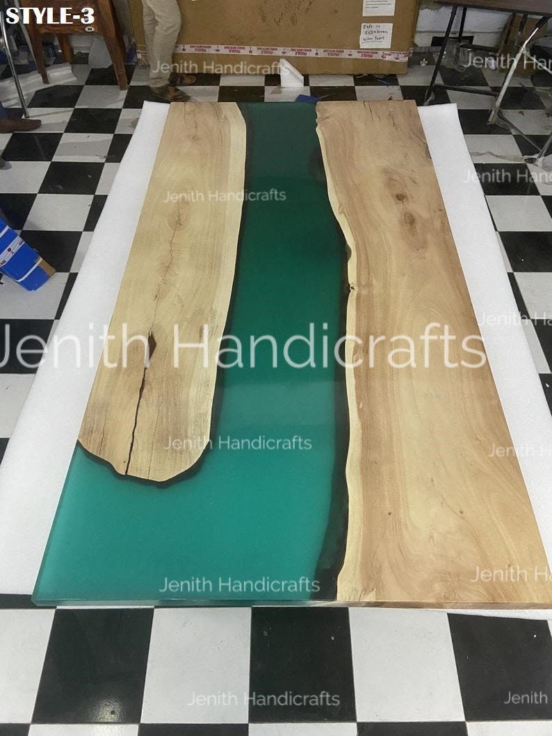 Op de afbeelding: Een groot houten tafelblad met een groene epoxyharsrivier die door het midden loopt. Het tafelblad is gemaakt van natuurlijk hout met een lichtbruine kleur. De epoxyhars is heldergroen en heeft een gladde, glanzende afwerking.