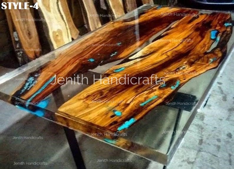 Op de afbeelding: Een houten tafelblad met een heldere epoxyharsafwerking. Het hout heeft een natuurlijke bruine kleur met turquoise blauwe accenten. Het tafelblad wordt ondersteund door een zwart metalen onderstel. "STYLE-4" staat in de linkerbovenhoek van de afbeelding.