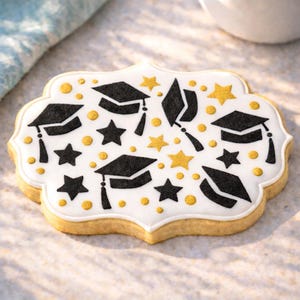 May include: A decorated sugar cookie with a white icing base. The cookie is adorned with black graduation caps, stars, and gold accents. The cookie has a scalloped edge and is a celebratory treat.
