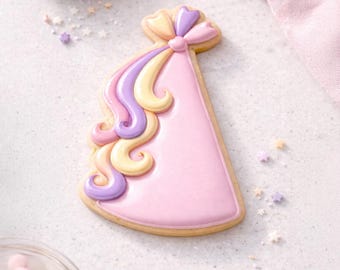 May include: A decorated sugar cookie shaped like a party hat. The hat is light pink with a yellow and purple bow and flowing icing in yellow, pink, and purple. Sprinkles and a small bowl of sprinkles are in the background.