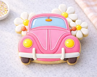 May include: A pink car-shaped cookie with yellow headlights and a blue windshield. The cookie is decorated with white and yellow daisy cookies. The car has brown tires and a white bumper. A small bowl of sprinkles is in the background.