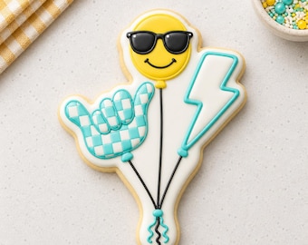 May include: A decorated sugar cookie in the shape of a balloon bouquet. The balloons include a yellow smiley face wearing sunglasses, a blue and white checkered hand, and a blue lightning bolt. Black strings and a yellow bow complete the design.
