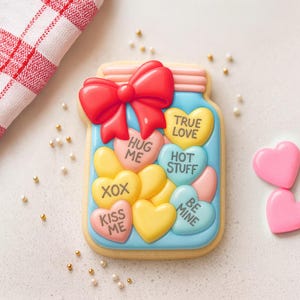 Pode incluir: Um biscoito de Dia dos Namorados em forma de pote cheio de doces em forma de coração. Os doces têm frases como "True Love" e "Be Mine". Um laço vermelho está em cima do pote. Dois doces em forma de coração rosa estão ao lado do biscoito.
