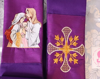 May include: Purple liturgical stole with embroidered religious imagery. One side features a family scene, the other a gold cross with floral accents. The stole is made of a shiny fabric.