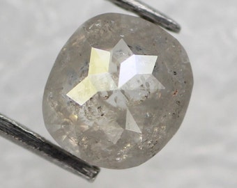 May include: A gray, faceted, oval-shaped diamond with a star-shaped pattern inside. The diamond is set in a silver setting.