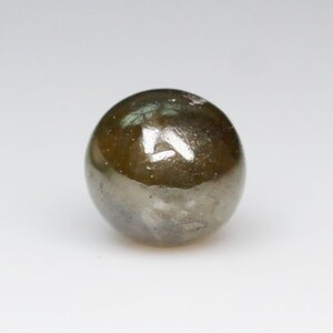 Puede incluir: Una piedra preciosa redonda de color verde oscuro con una superficie lisa y brillante.