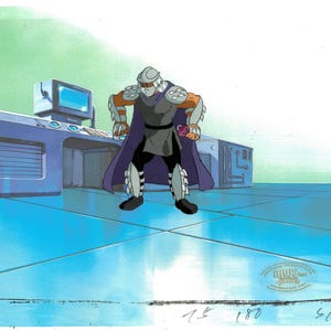 May include: An animation cel featuring the character Shredder from Teenage Mutant Ninja Turtles. Shredder is depicted in a gray and purple outfit with a silver helmet and armor. The background shows a futuristic laboratory setting.