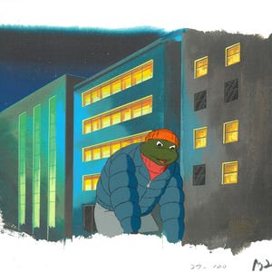 May include: Original animation cel featuring a turtle-like character in a blue puffer jacket, orange beanie, and red scarf, set against a backdrop of city buildings at night. The buildings have lit windows. The cel is signed.