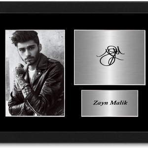 Puede incluir: Foto en blanco y negro enmarcada de un hombre con chaqueta de cuero, con una firma y una placa con el nombre "Zayn Malik". El marco es negro.