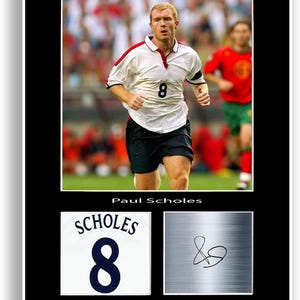 Könnte beinhalten: Gerahmter Druck mit Paul Scholes in einem weißen Fußballtrikot mit der Nummer 8. Das Bild enthält eine Nahaufnahme des Trikots, eine Unterschrift und ein Foto von Scholes auf dem Spielfeld.