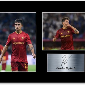 Op de afbeelding: Ingelijste print met twee afbeeldingen van een voetballer in een bordeauxrood shirt met nummer 21. De speler wordt in actie en feestend getoond. Een zilveren plaatje eronder toont een handtekening en de naam "Paulo Dybala."