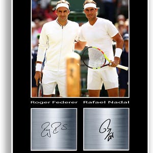 Può includere: Stampa incorniciata con Roger Federer e Rafael Nadal in abbigliamento da tennis. L'immagine include le loro firme in basso, su uno sfondo in metallo spazzolato. I giocatori indossano completi bianchi, Federer tiene una racchetta e Nadal una racchetta.
