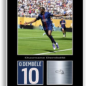 Pode incluir: Impressão emoldurada com Ousmane Dembélé em um jogo de futebol, vestindo uma camisa azul marinho com "Qatar Airways". Abaixo, um gráfico de camisa com "10" e um painel prateado com uma assinatura.